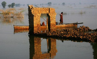 Des victimes des inondations passent en bateau parmi les maisons détruites du village de Chandan Mori Johi, Pakistan, le 30 septembre 2010.