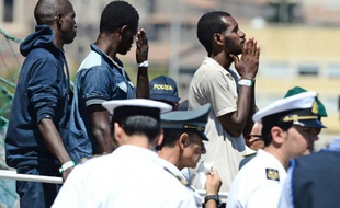 Des migrants patientent avant de débarquer dans le port italien de Catane, le 17 août 2015