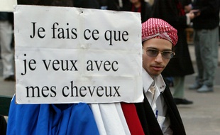 Farid Benyettou assis près d'une pancarte lors d'une manifestation en 2004.