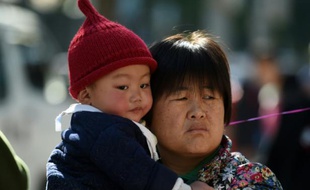 Une Chinoise tient un enfant dans ses bras, le 30 octobre 2015 à Pékin
