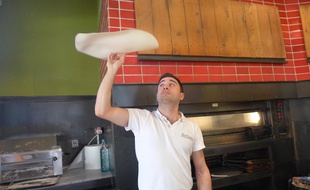 Davide fait tourner sa pâte à pizza dans la cuisine du restaurant Attimi, à Nice.