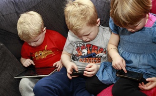 Trois enfants consultent leurs tablette et smartphone.
