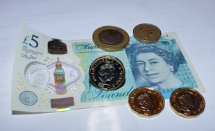 Un billet et des pièces de livre sterling. (illustration)