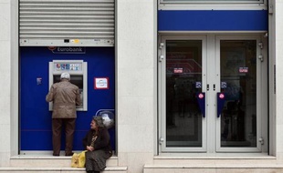 Une femme demande de l'argent devant le distributeur de billets d'une banque, le 6 avril 2015 à Athènes