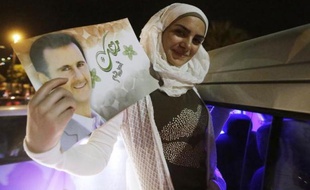 Une femme célèbre la victoire de Bachar al-Assad et brandit son portrait, après l'élection présidentielle, à Damas le 4 juin 2014