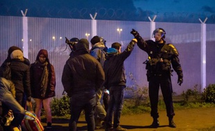 Un membre des forces de l'ordre face à des migrants, le 25 novembre 2015 à Calais