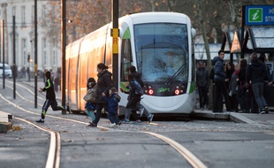 Des piétons traversant devant un tramway à Nantes.