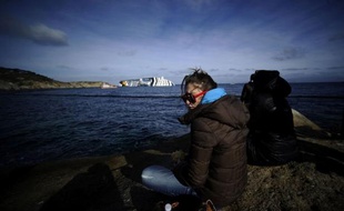 La carcasse du Concordia, échouée telle une énorme baleine à quelques dizaines de mètres de la rive, près de l'île toscane du Giglio, a attiré tout le week-end un tourisme macabre, des dizaines de curieux prenant la pose devant le navire de croisière géant.
