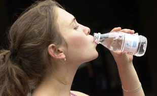 Une jeune femme boit de l'eau.