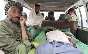 Des civils afghans près du corps d'une des victimes, le 11 mars 2012