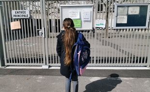 Une écolière devant une école fermée (illustration)