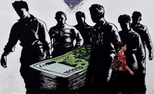 Une jeune femme passe devant un graffiti intitulé "la mort de l'euro" par l'artiste français Goin, le 19 juin dans le centre d'Athènes