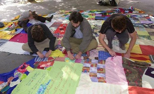 Des membres de l'association de solidarité Unis-Cité réalisent un patchwork composé de morceaux de tissus collectés partout en France, le 7 juin 2002 à Paris, dans le cadre de l'opération "le Patchwork des différences"