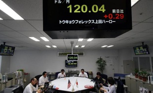 Des traders sous un tableau des taux de change, le 5 décembre 2014 à Tokyo