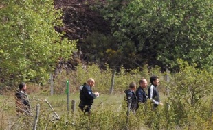 Berkane Makhlouf (à droite), le beau-père de Fiona, escorté par des officiers de police le 13 mai 2014 à Aydat, lors de la reprise des fouilles un an après la disparition de l'enfant.