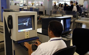Les bagages à main de passagers sont vérifiés par un membre de la sécurité de l'aéroport Roissy Charles-de-Gaulle, le 30 décembre 2009.