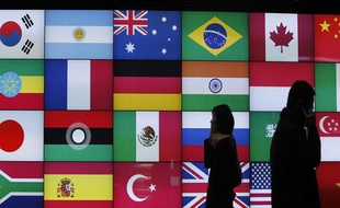 Des personnes devant un panneaux montrant les drapaux des pays du monde entier, lors du G20 de Séoul, le 5 novembre 2010.