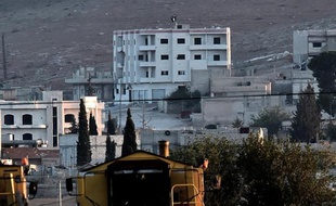 Un drapeau noir du groupe Etat Islamique flotte sur le toit d'un immeuble de la ville de Kobané, le 6 octobre 2014 en Syrie