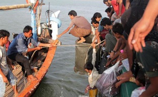 Des pêcheurs de la province d'Aceh en Indonésie (g) aident des migrants Rohingya à accoster près de la ville de Geulumpang, le 20 mai 2015